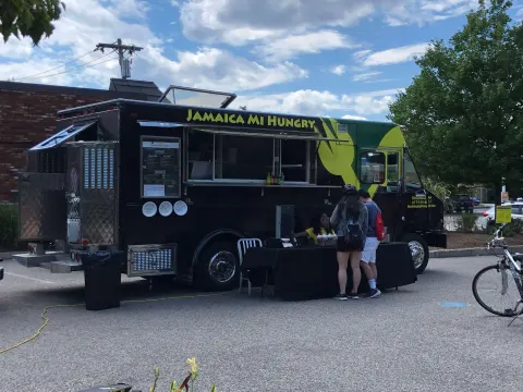 A Jamaican food truck with customers lined up outside