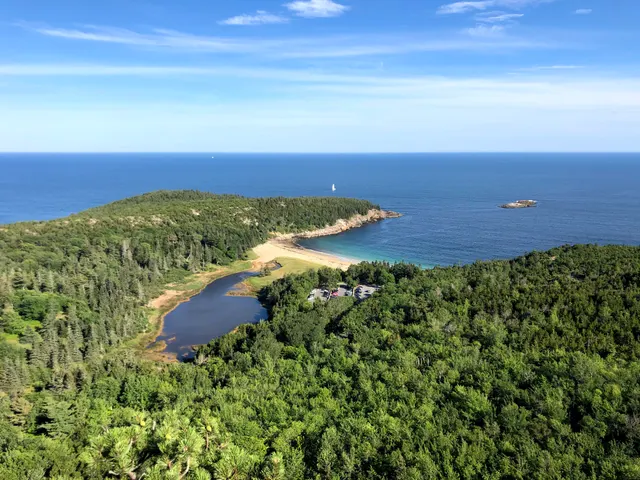 A sandy cove between forest and ocean in Acadia National Park, seen from above